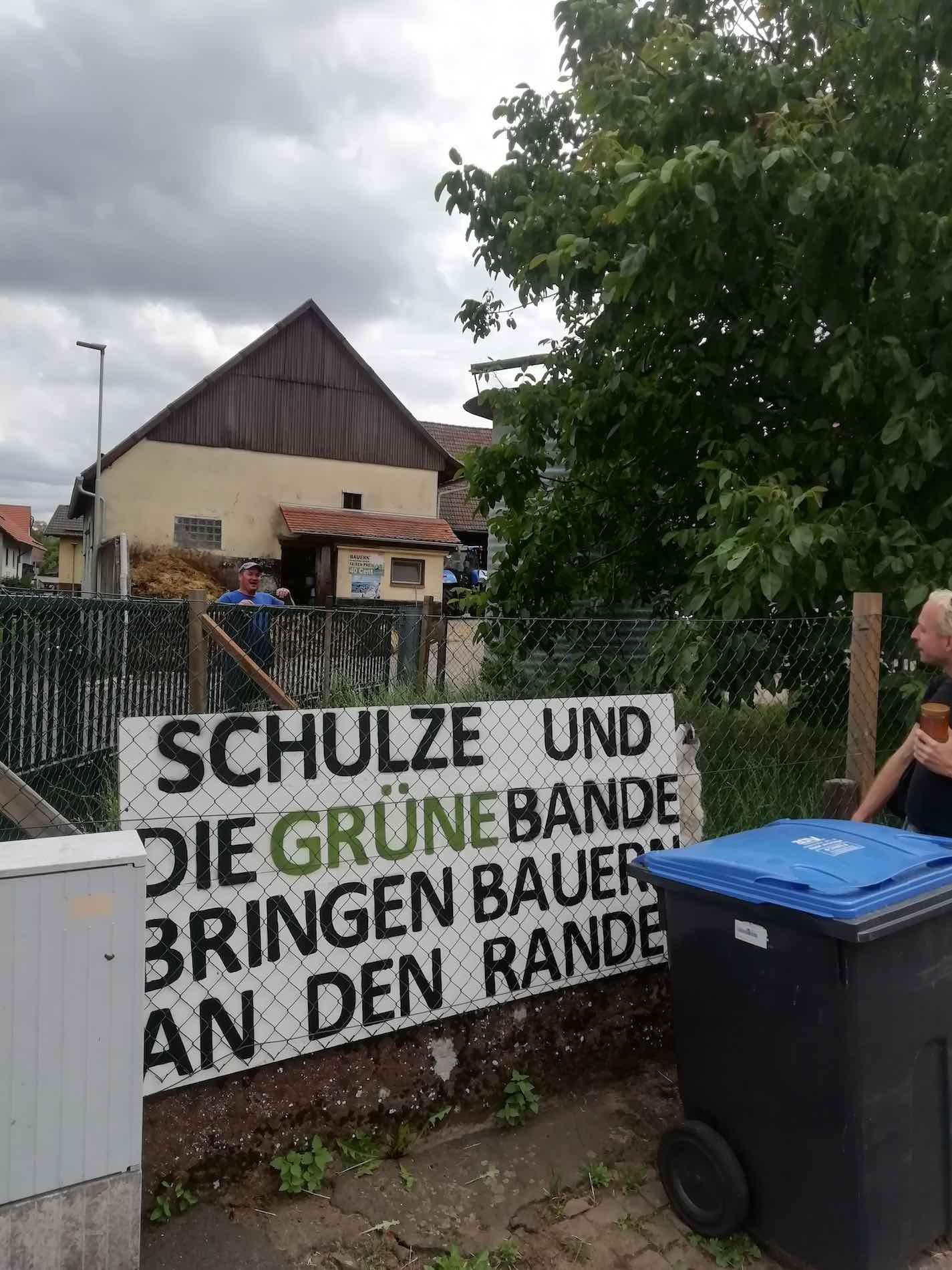 should-I-know in Schotten in conversation with a farmer who proclaims his opposition to the Green Party on a poster.