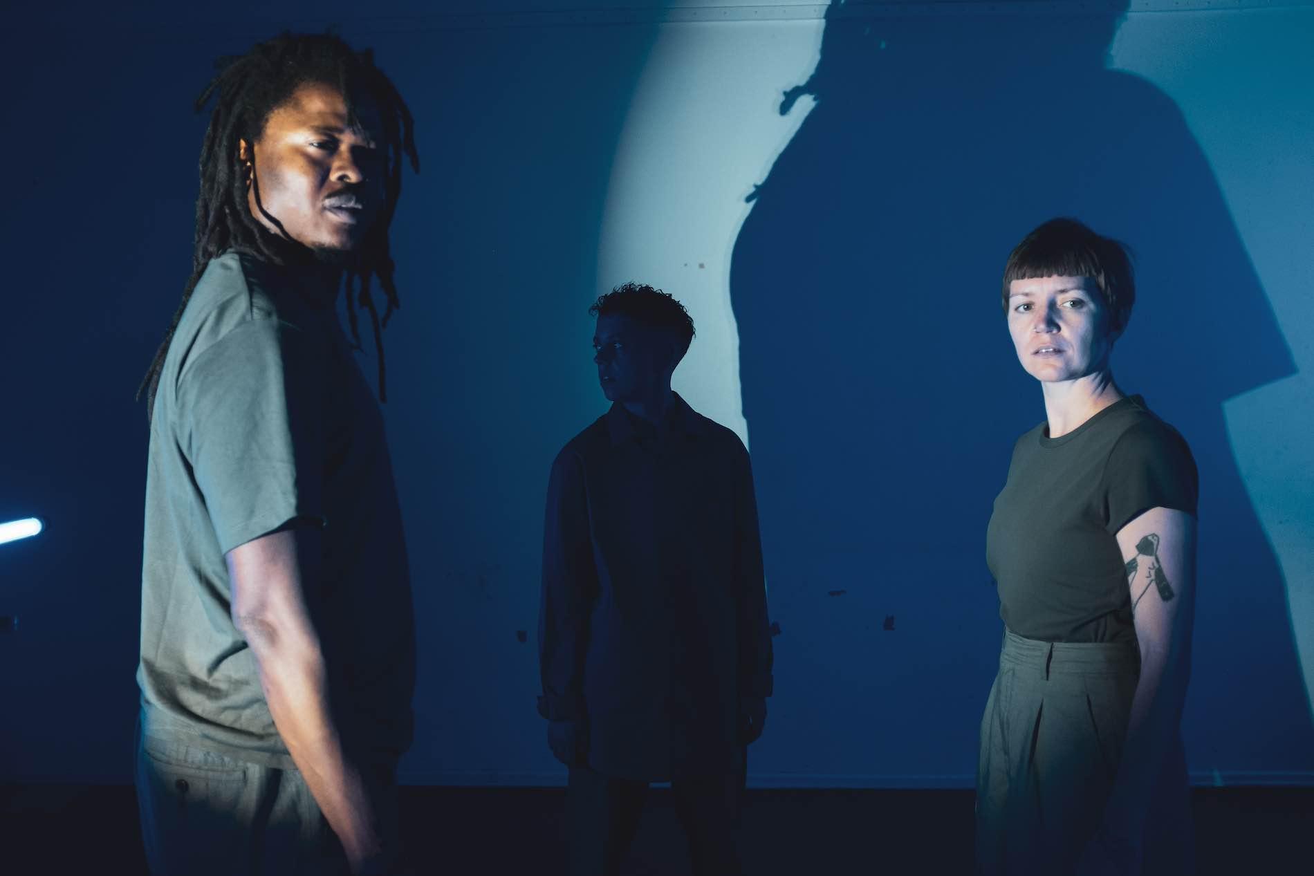 Illuminated by a flashlight, three people stand in the room and try to recognize the threat in the dark.