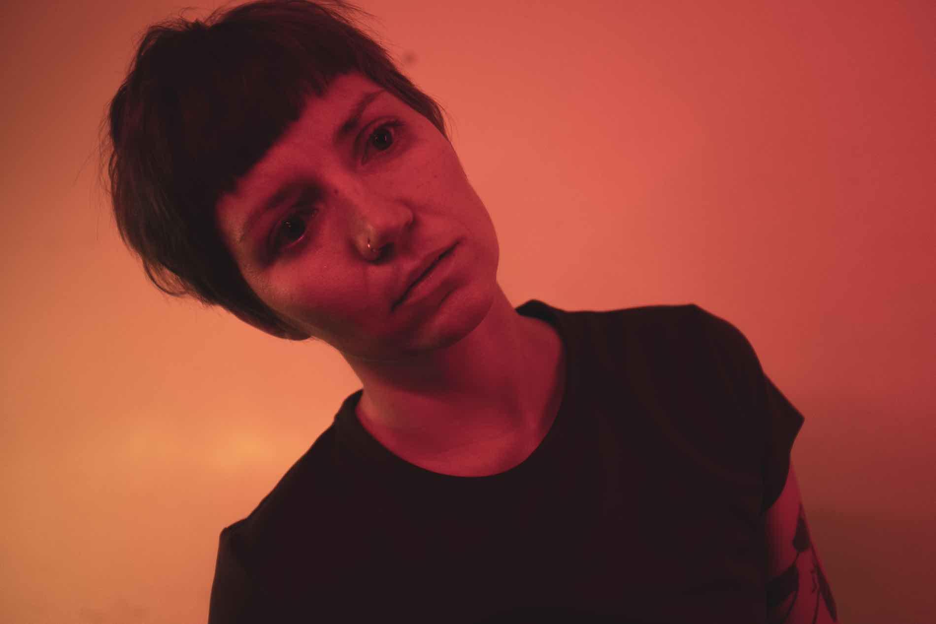 A person staggers unnaturally through the room in a severely tilted position. The face is expressionless and the gaze blank.